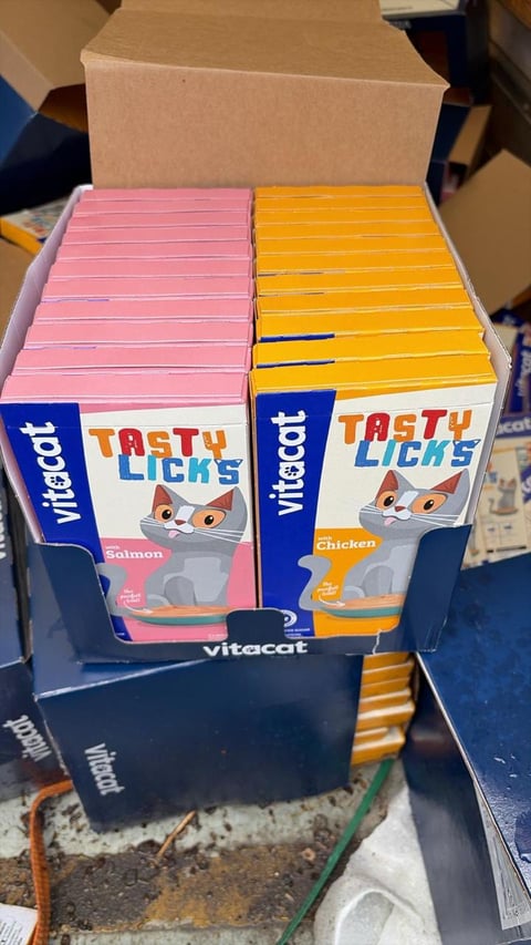 Cardboard box containing two stacks of Vitacat Tasty Licks cat treats in pink salmon and yellow chicken flavors