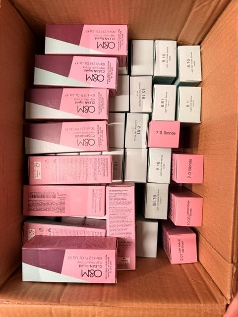 Flat lay of assorted beauty product boxes in pink and white arranged inside a cardboard shipping box