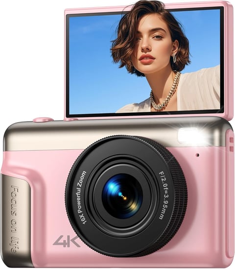 Pink compact digital camera with flip-up display screen showing womans portrait with clear blue sky background
