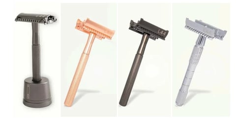 Collection of four safety razors in different finishes: dark metal pedestal model and three handheld versions in copper, black, and silver